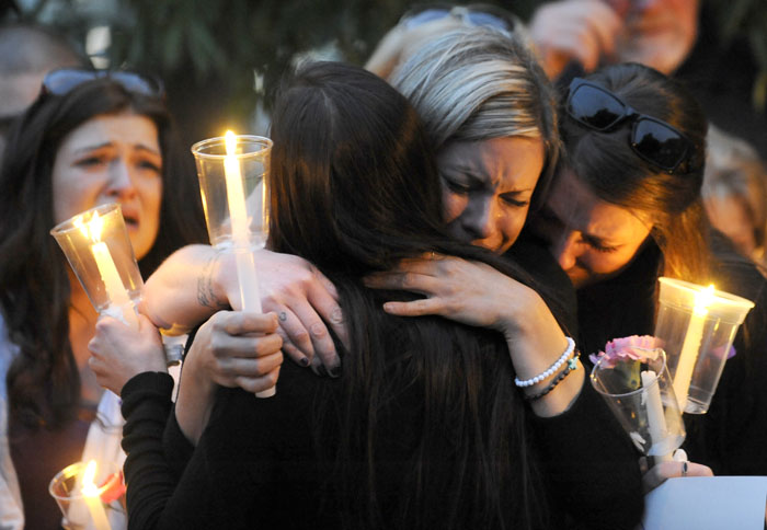 Carisa Meeker, center, and Brittany Stearns hug Jamie Roberts after Roberts talked about the type of person Monique Williams was during a candlelight vigil held at the John Dam Plaza in Richland on Friday, May 23, 2014. Williams (29) was killed in her home by her ex-boyfriend Aaron Newport on Monday in what officials are calling a murder-suicide.