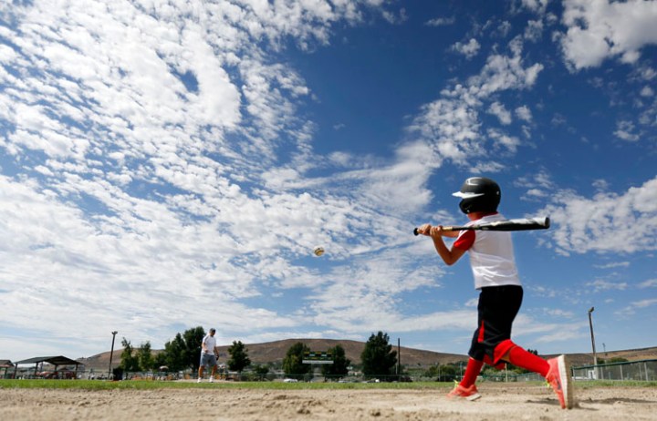 Rayce Reeves, 8, connects with a pitch from his dad, Ken, while doing batting practice at Badger Mountain Park along with his friend and neighbor Luke Parrott, 8, on Wednesday morning.