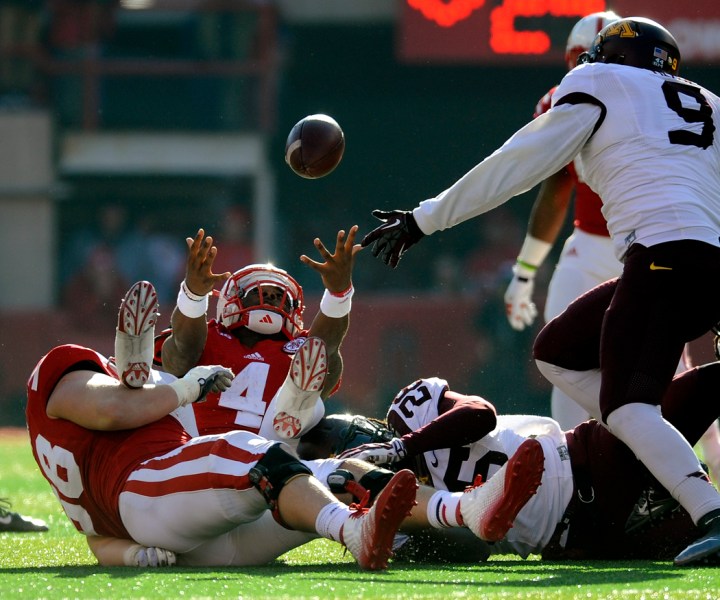 Nebraska Cornhuskers quarterback Tommy Armstrong Jr. (4) reaches out for the ball as he lost while being tackled by Minnesota Golden Gophers defensive back Jalen Myrick (28) during a game on Saturday at Memorial Stadium in Lincoln. Armstrong was ruled down on the play before losing control of the ball. (© Matt Gade)