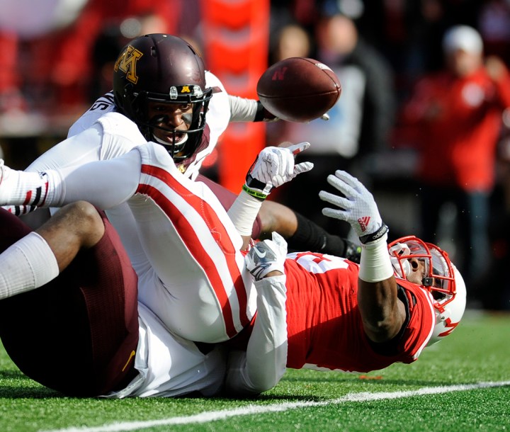 Nebraska Cornhuskers wide receiver De'Mornay Pierson-El (15) loses control of the ball out at the goal line as he was tackled by Minnesota Golden Gophers defensive back Damarius Travis (7) and Minnesota Golden Gophers defensive back Jalen Myrick (28) during a game on Saturday at Memorial Stadium in Lincoln. El was ruled to have crossed the goal line with the ball and the touchdown negated the fumble. (© Matt Gade)