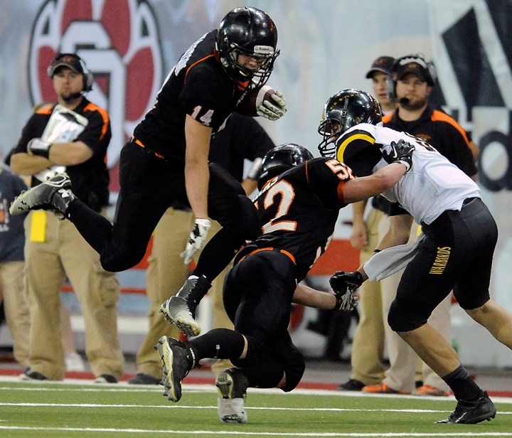 Howard's Gunner Gilbertson (14) leaps over his teammate Howard's Kaleb Haas (52) with the ball during the 9A state championship game on Thursday at the DakotaDome in Vermillion..(Matt Gade/Republic)