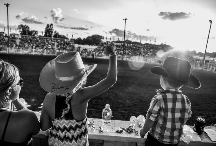 Eight-year-old Jaycee pumps her fist while watching the bareback riding competition with mom Caitlyn Lachnit, left, and brother Tayton (2), all of Alexandria, on Thursday night during the first night of the 45th annual Corn Palace Stampede Rodeo at Horseman Arena in Mitchell.(Matt Gade/Republic)